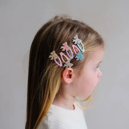 Side profile of a young girl with pastel butterfly hair clips along the side of her head.