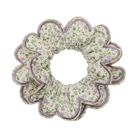 Flower-shaped fabric scrunchie with lavender trim and a cream background patterned in green and purple flowers (hair accessory).