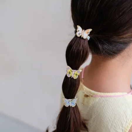 Child's dark braid decorated with three pastel butterfly hair clips