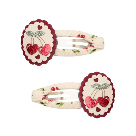 Pair of fabric hair clips with cream floral band and red scalloped circles featuring cherry-heart embellishments.