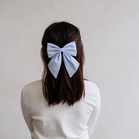 Back view of a person with dark hair wearing a light blue striped bow in their hair