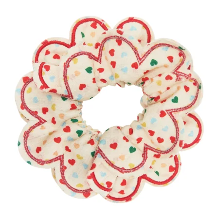 Hair scrunchie with a cream fabric and red-stitched heart border, covered in small multicolored hearts.