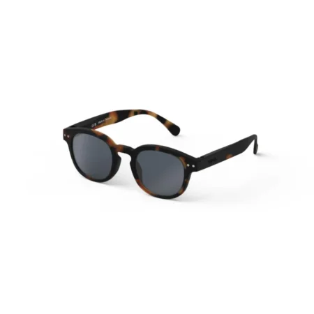 Tortoiseshell sunglasses with dark gray lenses resting on a white background.