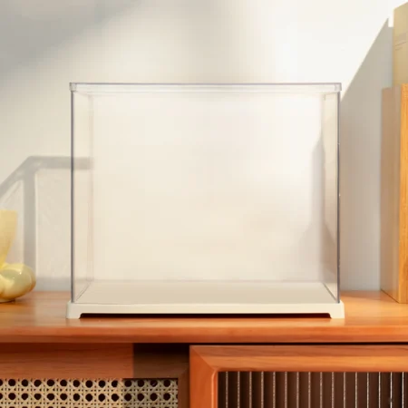 Clear glass display case with a white base on a wooden shelf, currently empty inside.