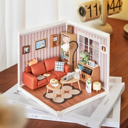 Miniature dollhouse living room with a red sofa, coffee tables, and small kitchen area against pink striped walls.