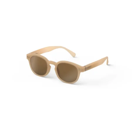 Beige sunglasses with brown lenses resting on a white background.