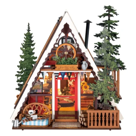 Detailed wooden diorama of a chalet with a triangular roof, kitchen items, flags, and trees, resembling a cozy alpine scene.