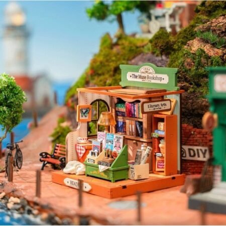Miniature bookshop diorama labeled The Muse Bookshop with shelves of books and a 'Literary Arts' sign on a green storefront.