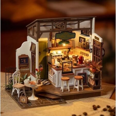 Miniature coffee shop scene with a counter, stools, and a small dining table on a wooden base; warm lighting in a dollhouse setting to convey a cozy café interior.