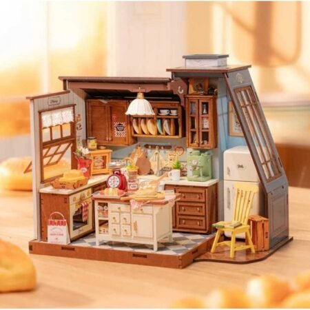Miniature wooden kitchen playset with stove, fridge, and dishes arranged on a tiled base, open doors showing cupboards and shelves.