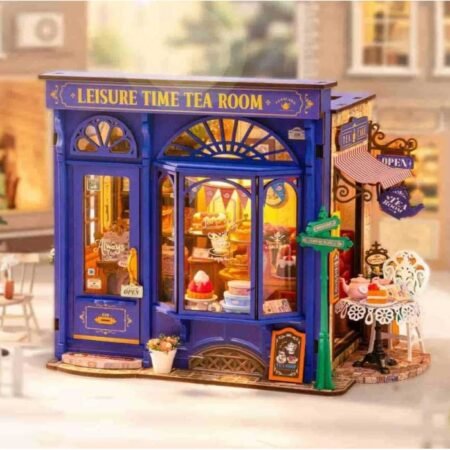 Colorful miniature blue storefront labeled 'Leisure Time Tea Room' with cake displays in the window and outdoor seating area.