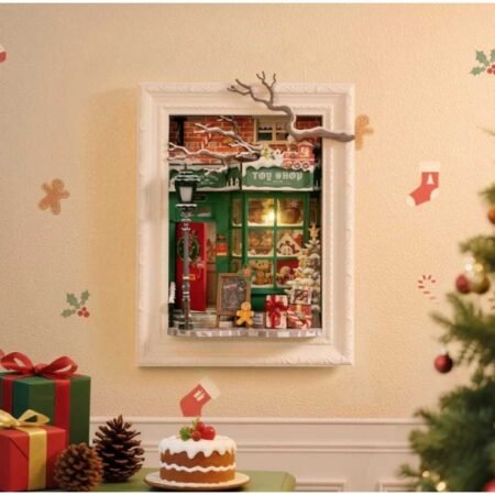 Framed miniature toy shop scene on a wall with Christmas decorations and a cake in front.