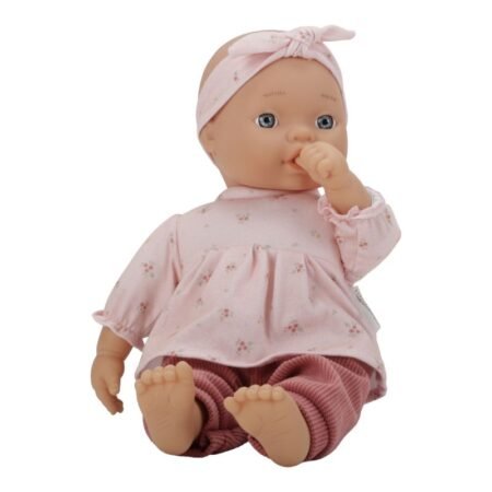 Soft pink-clad baby doll with a headband, sitting with one finger in its mouth.