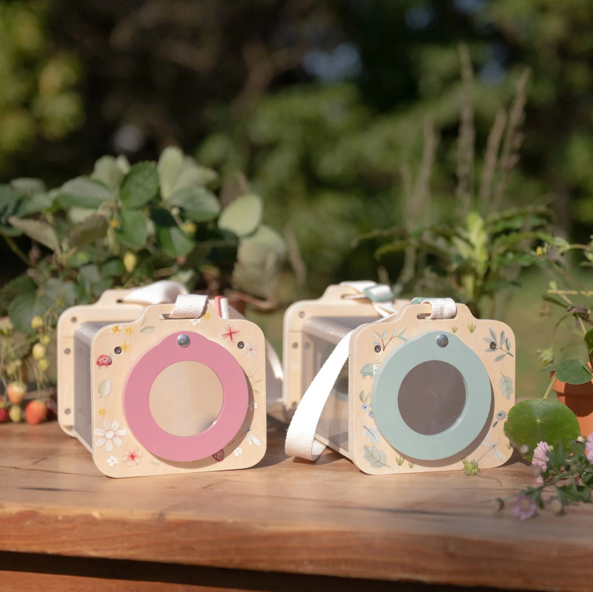 image_40801 Row of pastel gift boxes with circular pink and blue panels and fabric straps on a wooden table outdoors.