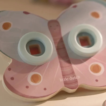 Pastel pink wooden baby toy with light blue rings and two circular openings, Little Dutch brand visible on the surface