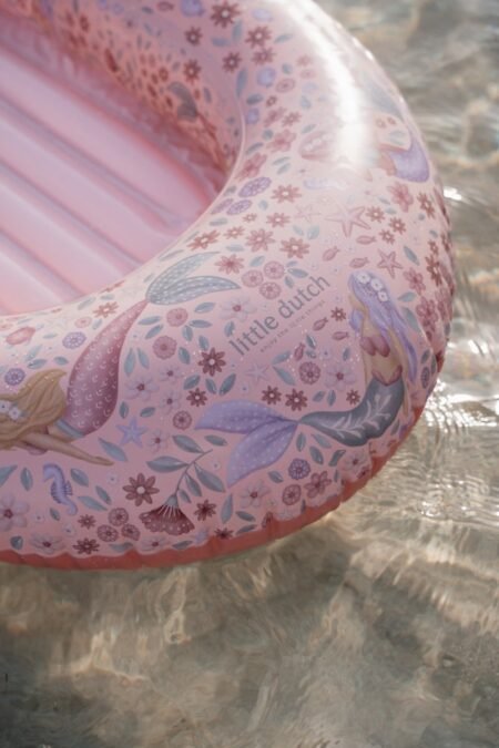 Pink inflatable swim ring with mermaid and floral pattern, floating on water